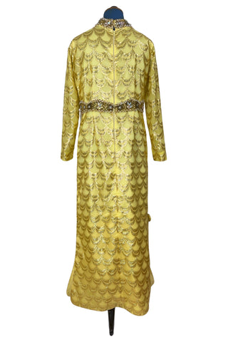 Absolutely stunning true vintage 1960s evening gown in gold metallic figured sheer chiffon, with intricate heavy beading at the high neckline and waist, with large beaded medallion clusters at the tops of the side slits in the skirt. The dress is lined through the bodice and skirt, while the sleeves are left unlined to highlight the sheer gold fabric. 

Designed and made by Fontana’s New York. 

The dress closes in the back with a cotton twill nylon zipper.