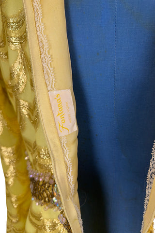 Absolutely stunning true vintage 1960s evening gown in gold metallic figured sheer chiffon, with intricate heavy beading at the high neckline and waist, with large beaded medallion clusters at the tops of the side slits in the skirt. The dress is lined through the bodice and skirt, while the sleeves are left unlined to highlight the sheer gold fabric. 

Designed and made by Fontana’s New York. 

The dress closes in the back with a cotton twill nylon zipper.