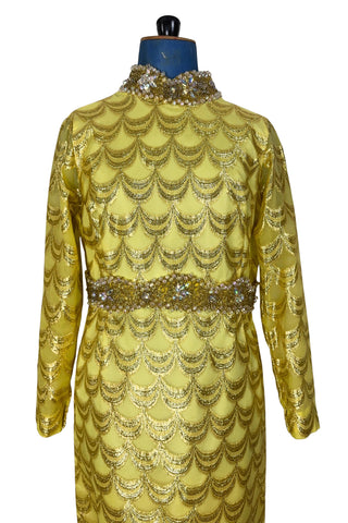 Absolutely stunning true vintage 1960s evening gown in gold metallic figured sheer chiffon, with intricate heavy beading at the high neckline and waist, with large beaded medallion clusters at the tops of the side slits in the skirt. The dress is lined through the bodice and skirt, while the sleeves are left unlined to highlight the sheer gold fabric. 

Designed and made by Fontana’s New York. 

The dress closes in the back with a cotton twill nylon zipper.
