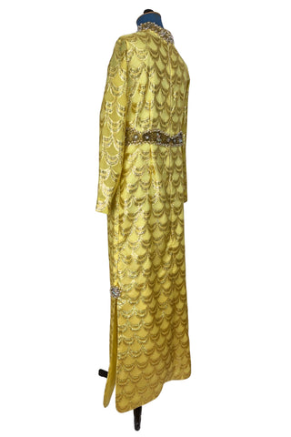 Absolutely stunning true vintage 1960s evening gown in gold metallic figured sheer chiffon, with intricate heavy beading at the high neckline and waist, with large beaded medallion clusters at the tops of the side slits in the skirt. The dress is lined through the bodice and skirt, while the sleeves are left unlined to highlight the sheer gold fabric. 

Designed and made by Fontana’s New York. 

The dress closes in the back with a cotton twill nylon zipper.