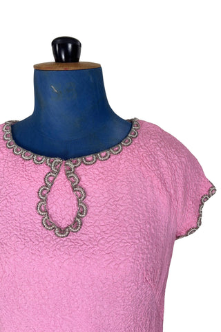 Stunning true vintage 1960s evening gown in candy pink textured crepe with scalloped silver beading at the neckline and trimming the short sleeve cuffs.

The gown is designed with a close-fitting column silhouette, while the textured crepe molds beautifully to your curves.

The gown is fully lined and closes in the back with a cotton twill nylon zipper.