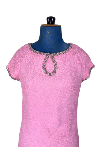 Stunning true vintage 1960s evening gown in candy pink textured crepe with scalloped silver beading at the neckline and trimming the short sleeve cuffs.

The gown is designed with a close-fitting column silhouette, while the textured crepe molds beautifully to your curves.

The gown is fully lined and closes in the back with a cotton twill nylon zipper.