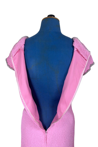 Stunning true vintage 1960s evening gown in candy pink textured crepe with scalloped silver beading at the neckline and trimming the short sleeve cuffs.

The gown is designed with a close-fitting column silhouette, while the textured crepe molds beautifully to your curves.

The gown is fully lined and closes in the back with a cotton twill nylon zipper.