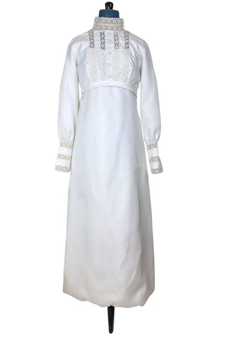 Vintage late 1960s or early 1970s wedding dress with high neck, long sleeves, and an empire waist. This Edwardian revival style dress features crochet lace panels at the neck, down the front and back of the bodice, and trimming the long sleeve cuffs. The dress has a large flat bow at the back of the waist.

Channel your inner Priscilla Presley in this lovely vintage gown.

The dress closes in the back with a cotton twill nylon zipper.