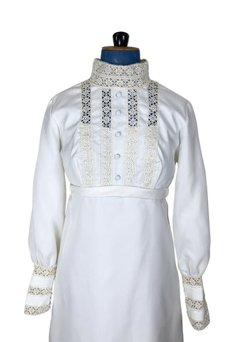 Vintage late 1960s or early 1970s wedding dress with high neck, long sleeves, and an empire waist. This Edwardian revival style dress features crochet lace panels at the neck, down the front and back of the bodice, and trimming the long sleeve cuffs. The dress has a large flat bow at the back of the waist.

Channel your inner Priscilla Presley in this lovely vintage gown.

The dress closes in the back with a cotton twill nylon zipper.