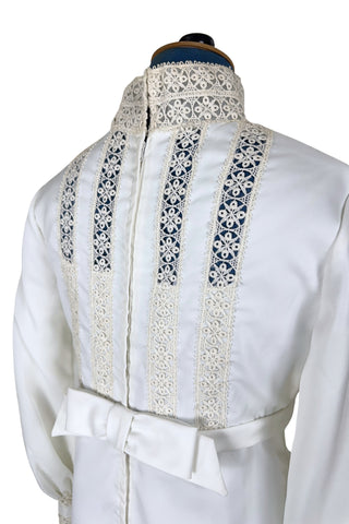 Vintage late 1960s or early 1970s wedding dress with high neck, long sleeves, and an empire waist. This Edwardian revival style dress features crochet lace panels at the neck, down the front and back of the bodice, and trimming the long sleeve cuffs. The dress has a large flat bow at the back of the waist.

Channel your inner Priscilla Presley in this lovely vintage gown.

The dress closes in the back with a cotton twill nylon zipper.