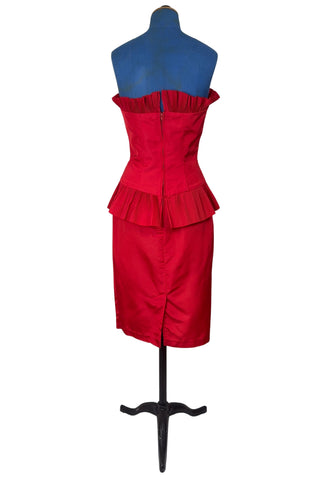 Vintage late 1980s or early 1990s cocktail dress in bold red acetate faille fabric with subtle ribbed texture. The strapless bodice has a wrapped appearance, trimmed with wide panels of accordion pleated ruffles. A large bow at the waist is crowned with a wide band of rhinestones.

Designed with an hourglass silhouette, the dress hugs and accentuates curves for a bombshell fit. 

Marked size 9/10 (vintage sizing - see measurements section at right).

Designed by Collections JS. Made in Canada.